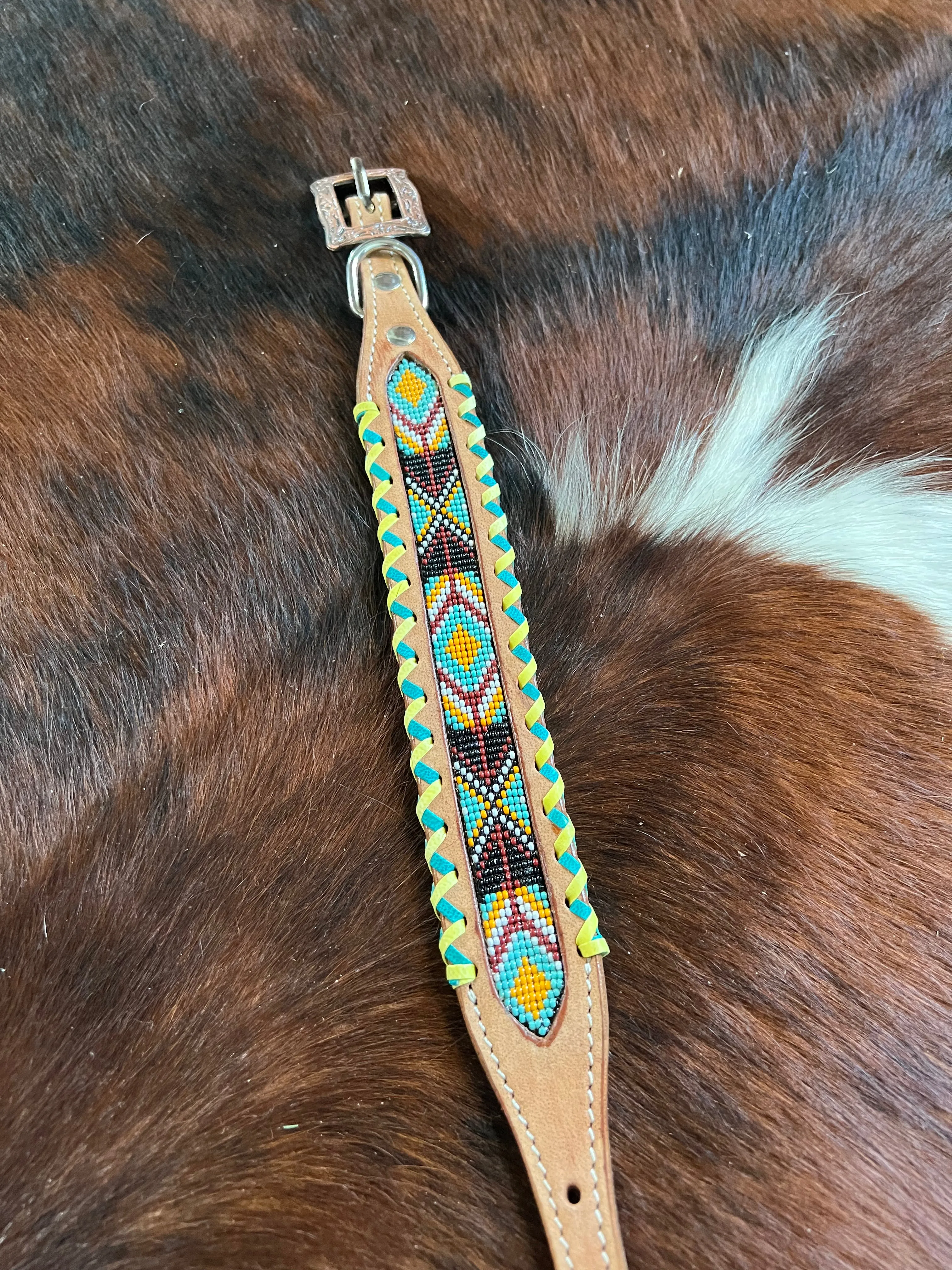 Genuine leather dog collar with teal, white, yellow and burgundy navajo beaded inlay design, a rawhide wrapped edge